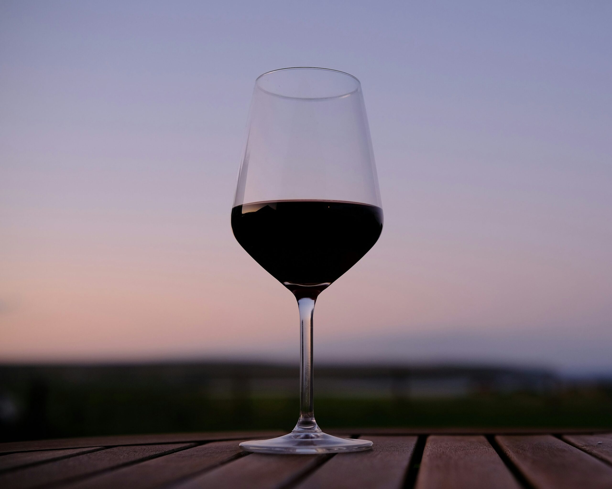 a glass of wine sitting on top of a wooden table