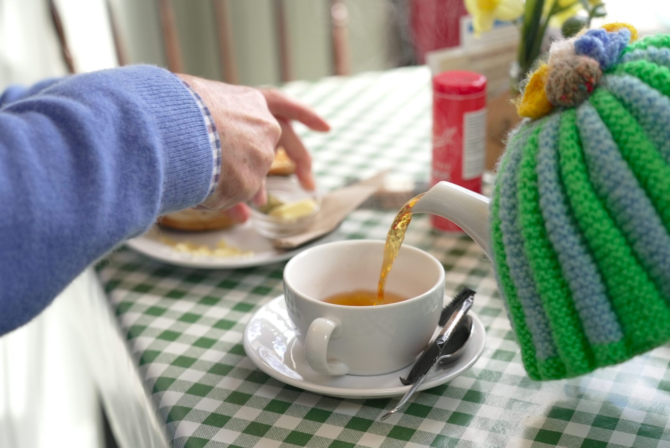 A person pouring tea into a cup on a table
