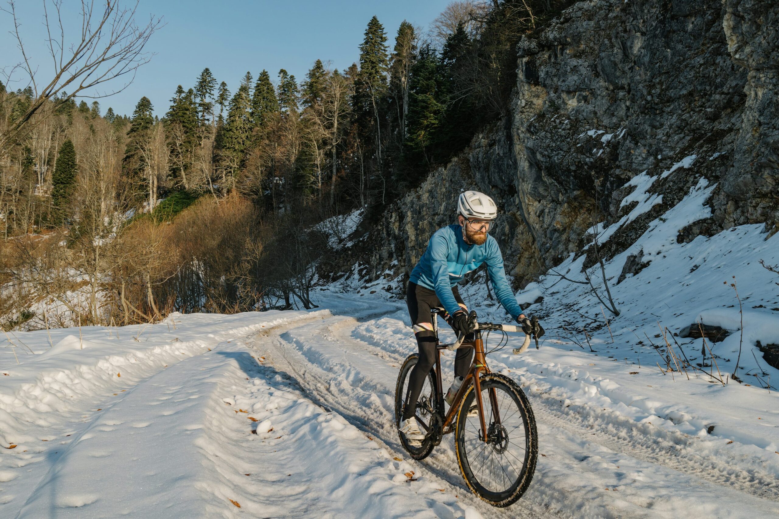 a man riding a bike down a snow covered road